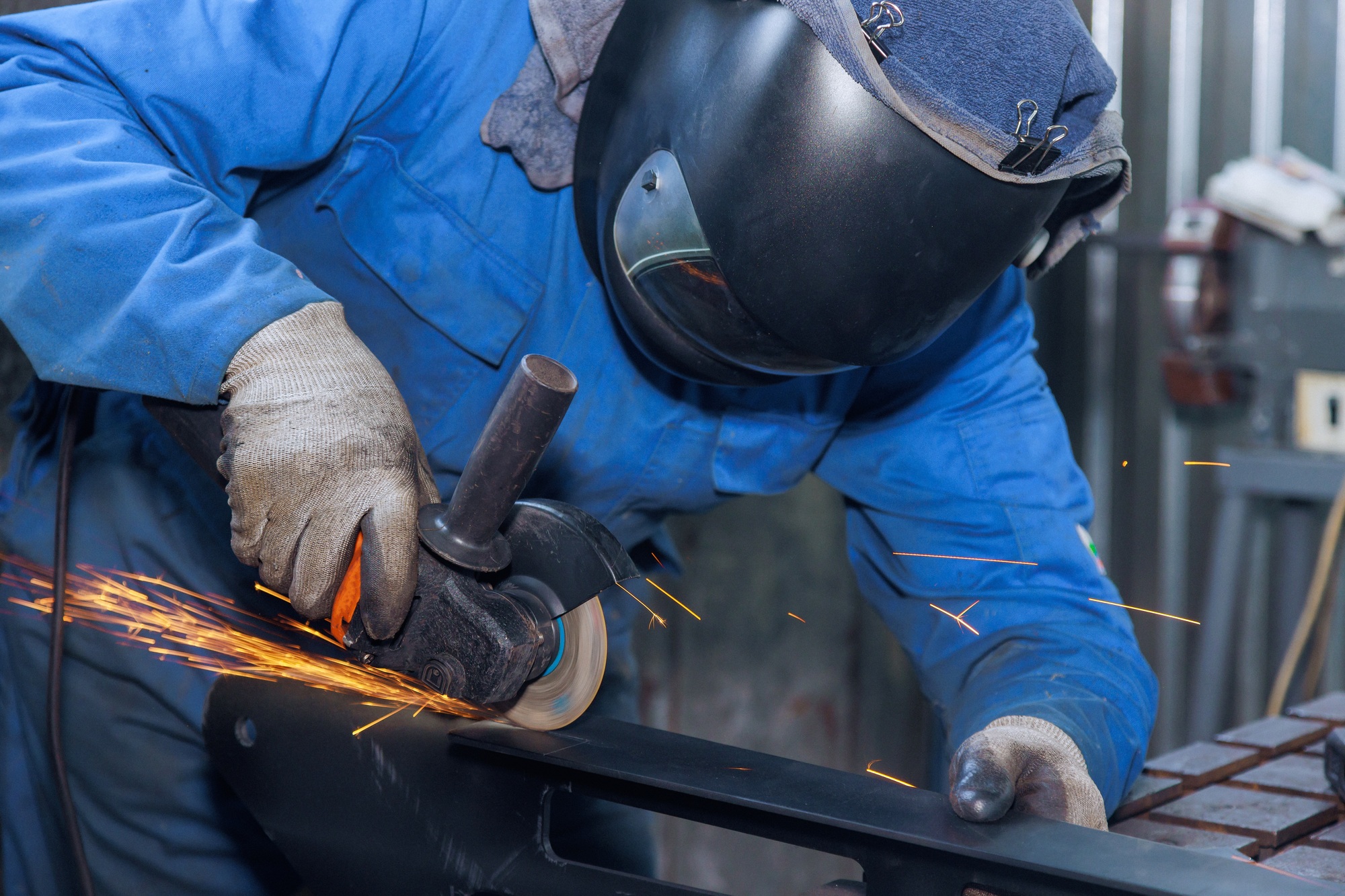 Metalwork workplaces are in the factory with a master grinding metal and sparks are flying